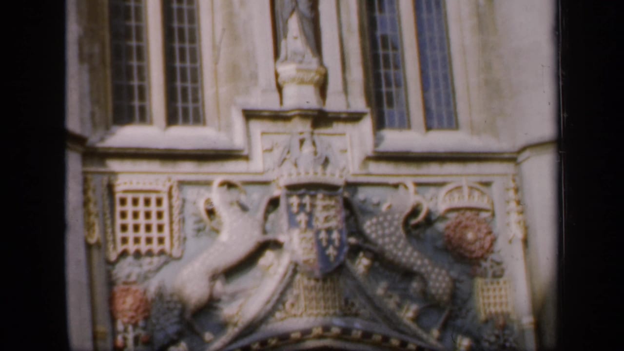 Carved coat of arms below tall windows on a stone facade.
