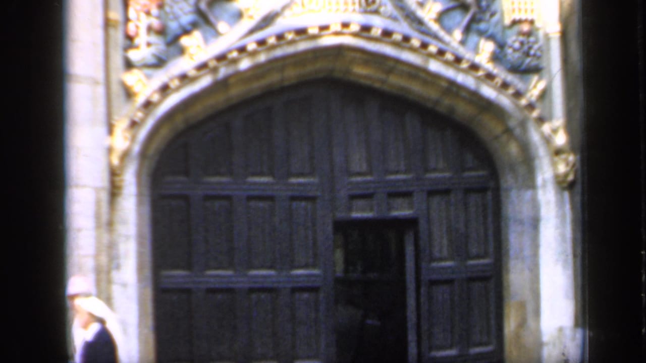 A large arched cathedral doorway in England, with ornate carved stone figures above the dark timber doors.