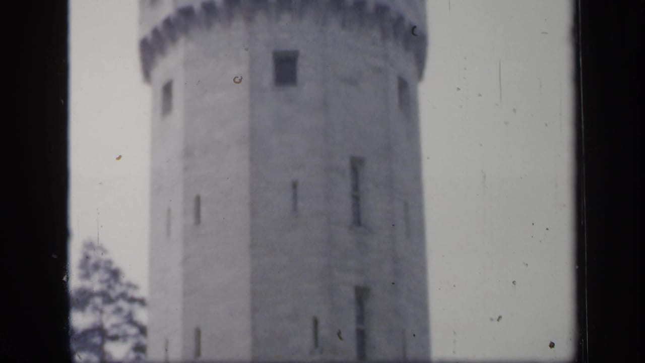 1949 England 8mm frame showing a round stone castle tower with small vertical windows and a blurred parapet edge.