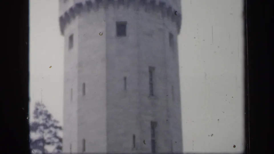 1949 England 8mm frame showing a round stone castle tower with small vertical windows and a blurred parapet edge.