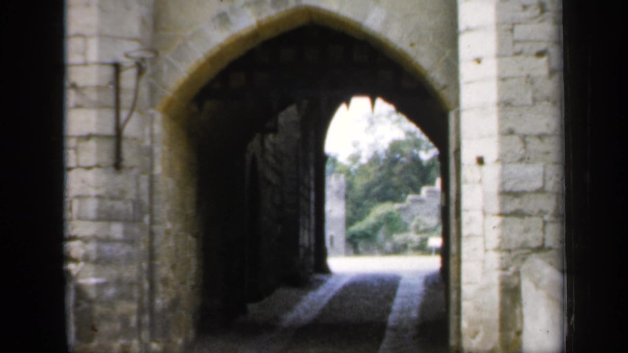 Stone castle passage seen from inside, with an arched opening and bright courtyard beyond.
