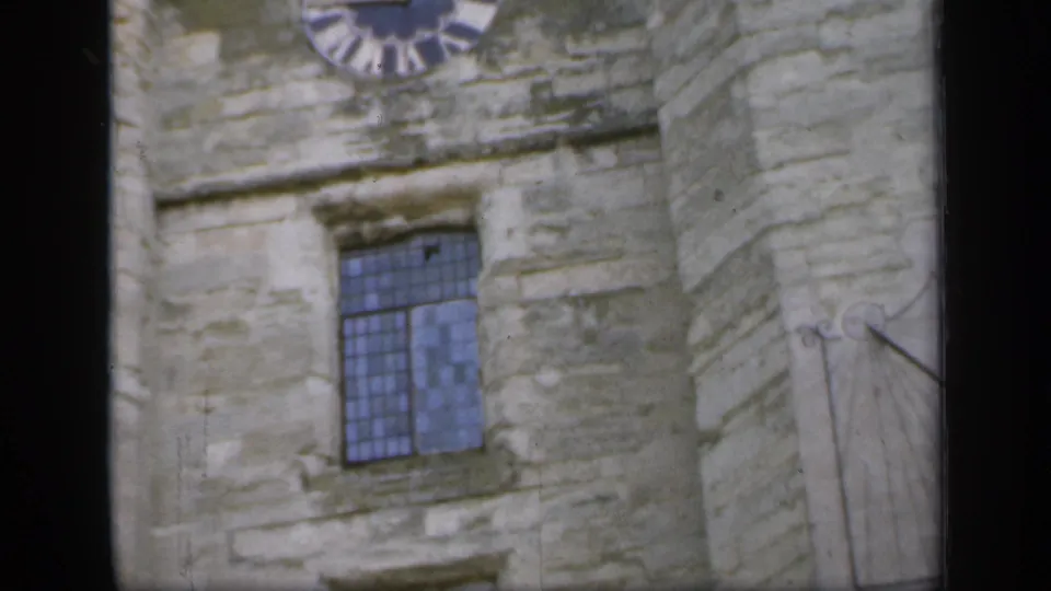 1949 England frame showing a partial clock face above a leaded window with a sundial at the edge.