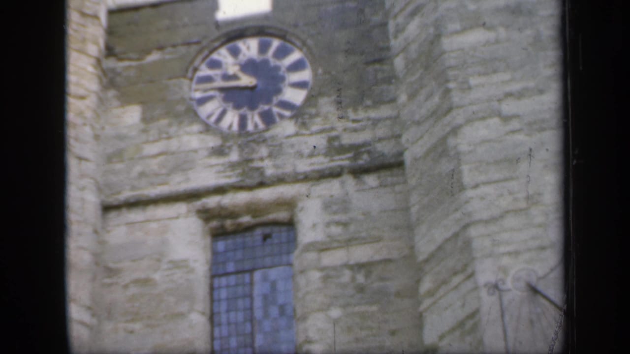 1949 England frame with the castle clock face high on the stone wall and a leaded window below.