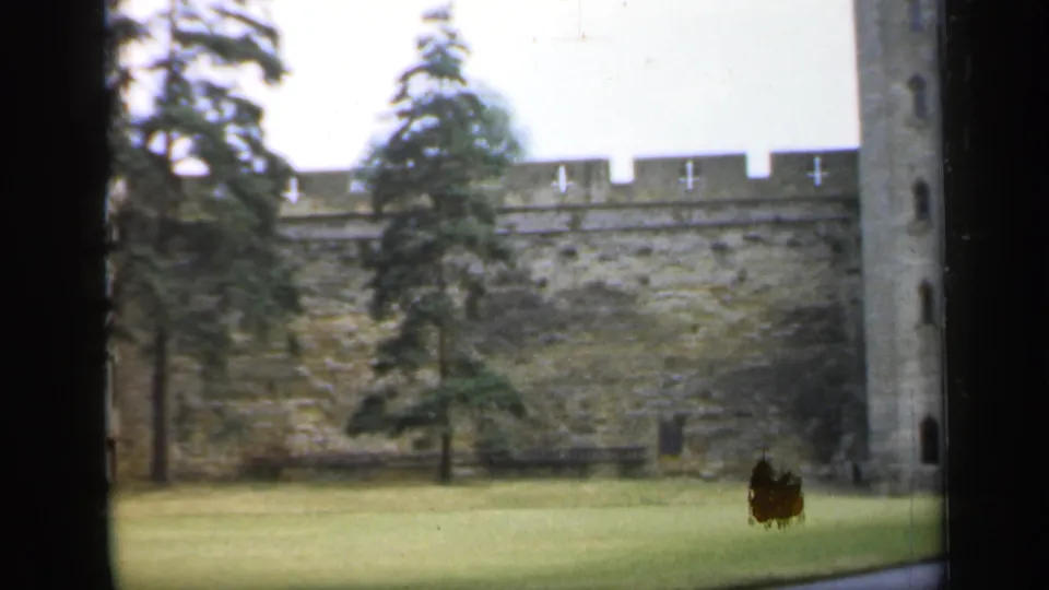 Soft 8mm frame of an English castle wall, trees, lawn, and partial tower, dated 1949 by clip metadata.