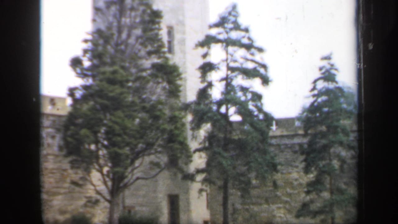 Stone castle tower, battlements, and trees in a soft 8mm frame from England in 1949.