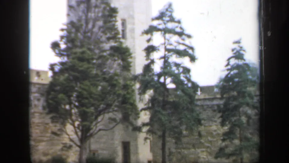 Stone castle tower, battlements, and trees in a soft 8mm frame from England in 1949.