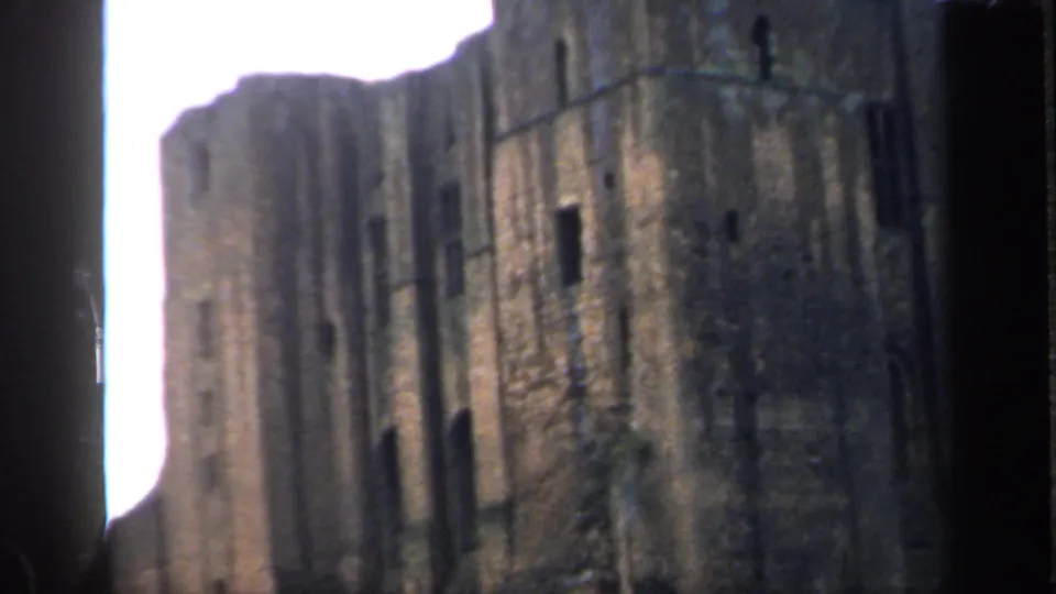 Close 1949 England view of a weathered castle ruin, showing high stonework and small dark window openings.