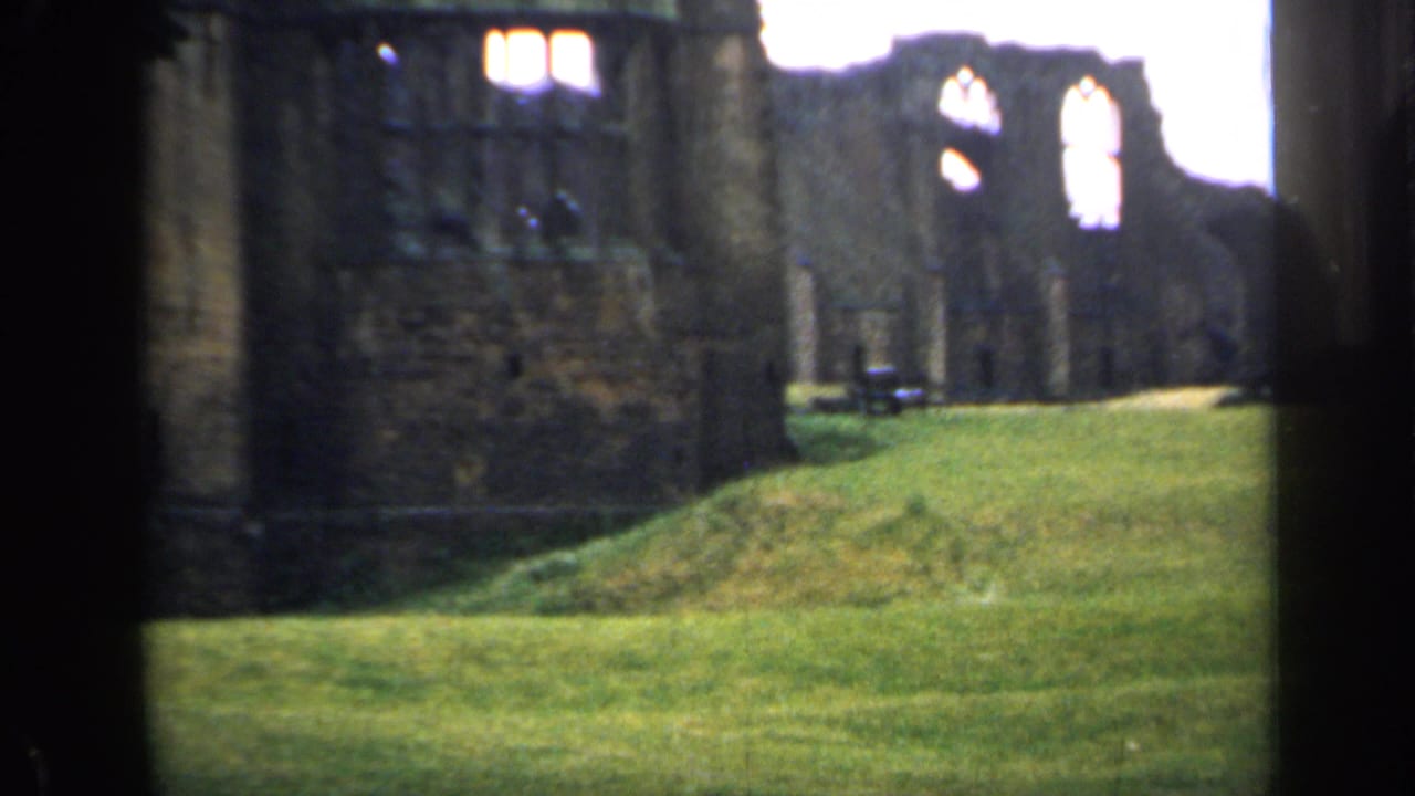 Stone ruin with tall window openings and a grassy foreground.