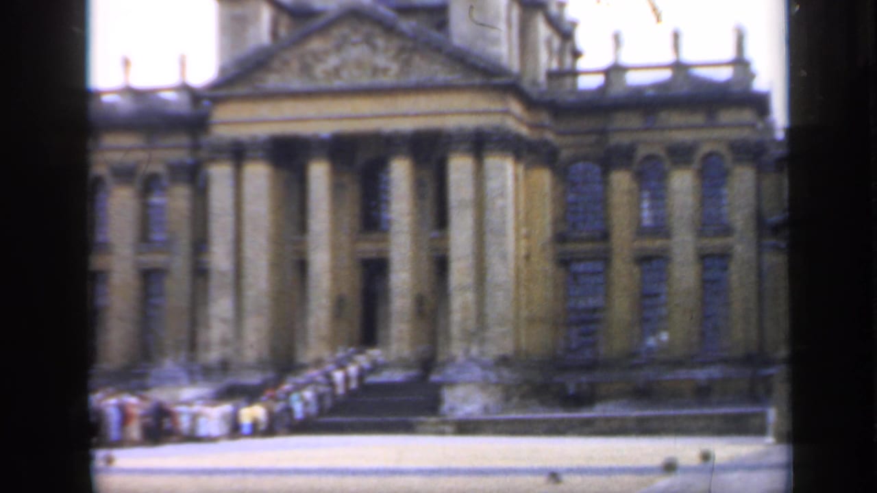 1949 England home-movie view of a grand classical stone building with tall columns, a pediment, steps, and distant visitors near the entrance.