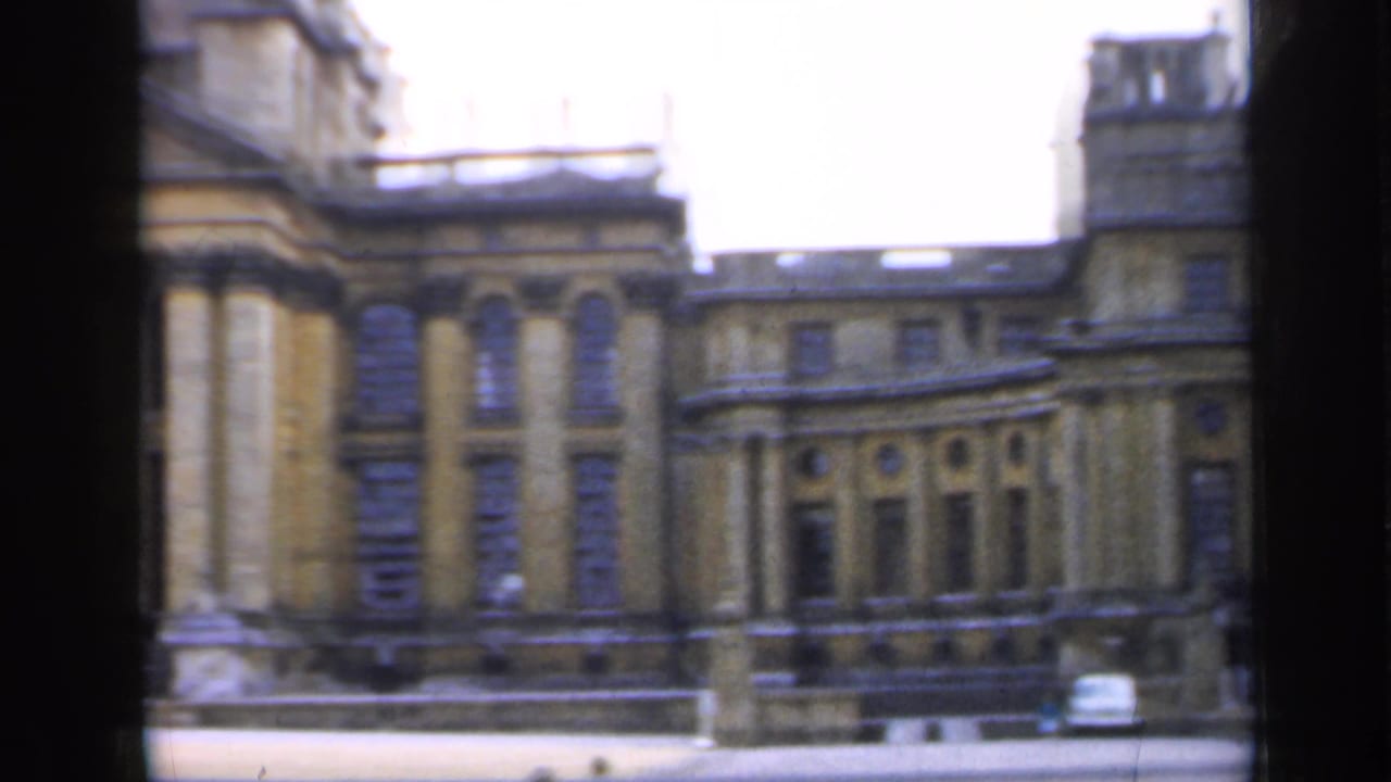 1949 England view across part of the building, showing arched windows, roofline details, a curved facade section, and a small car near the base.