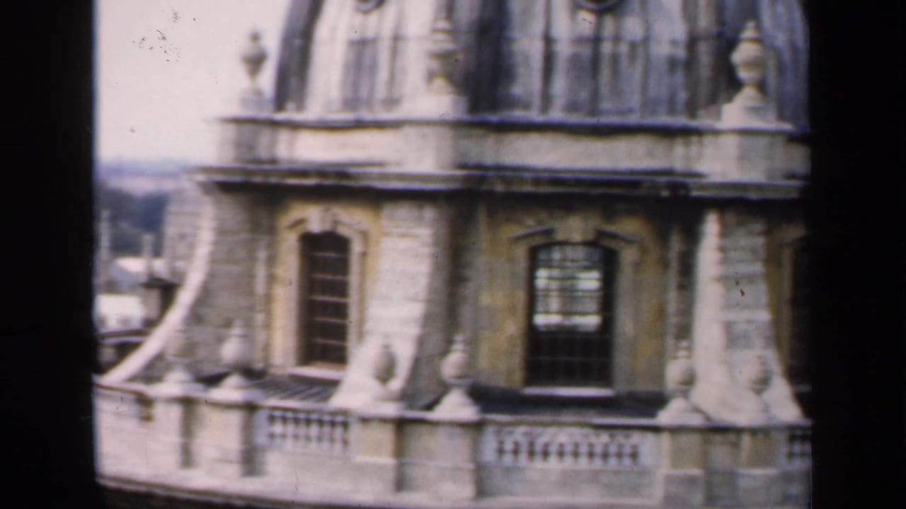 Close view of an ornate stone tower with windows, balustrade and curved roof details.