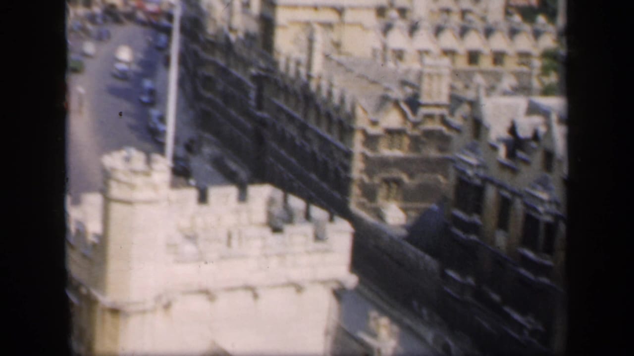 Historic stone tower and dark roofline above a street with cars.