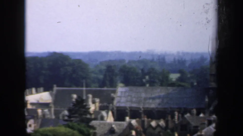 Final 1949 England view looking past town rooftops and trees toward open countryside under a pale sky.