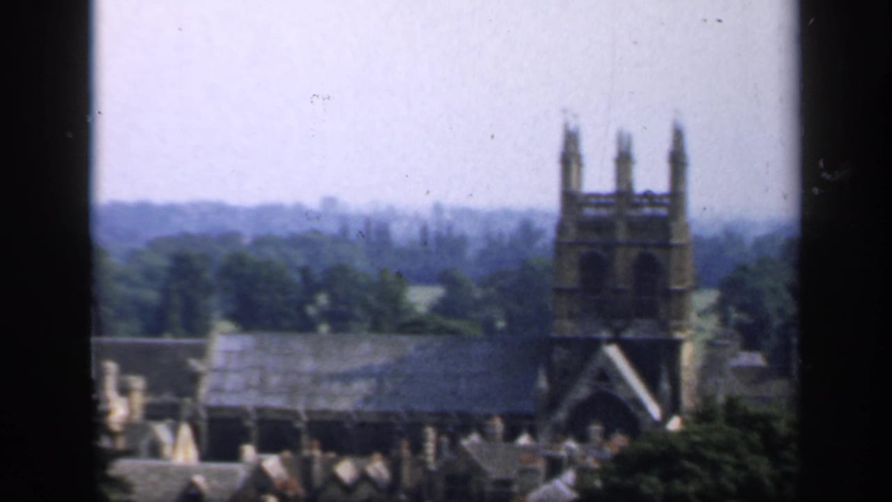 Gothic church tower and rooftops seen through a dark window frame.