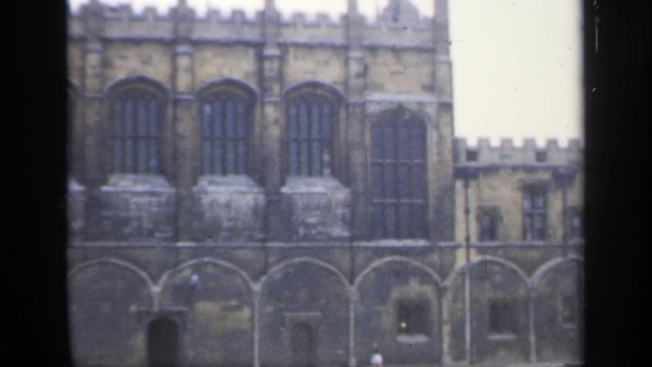 Crenellated stone building with tall arched windows and a courtyard below.