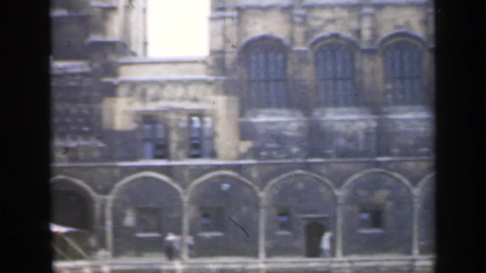 The 1949 England footage shows a stone corner with arched windows, lower openings, and small distant people near the facade.
