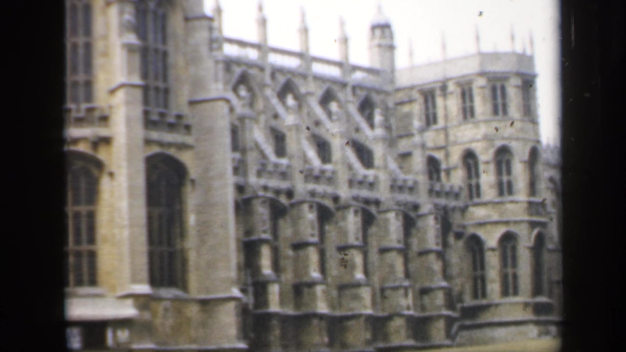 Gothic stone building with arched windows and buttresses beside a lawn.