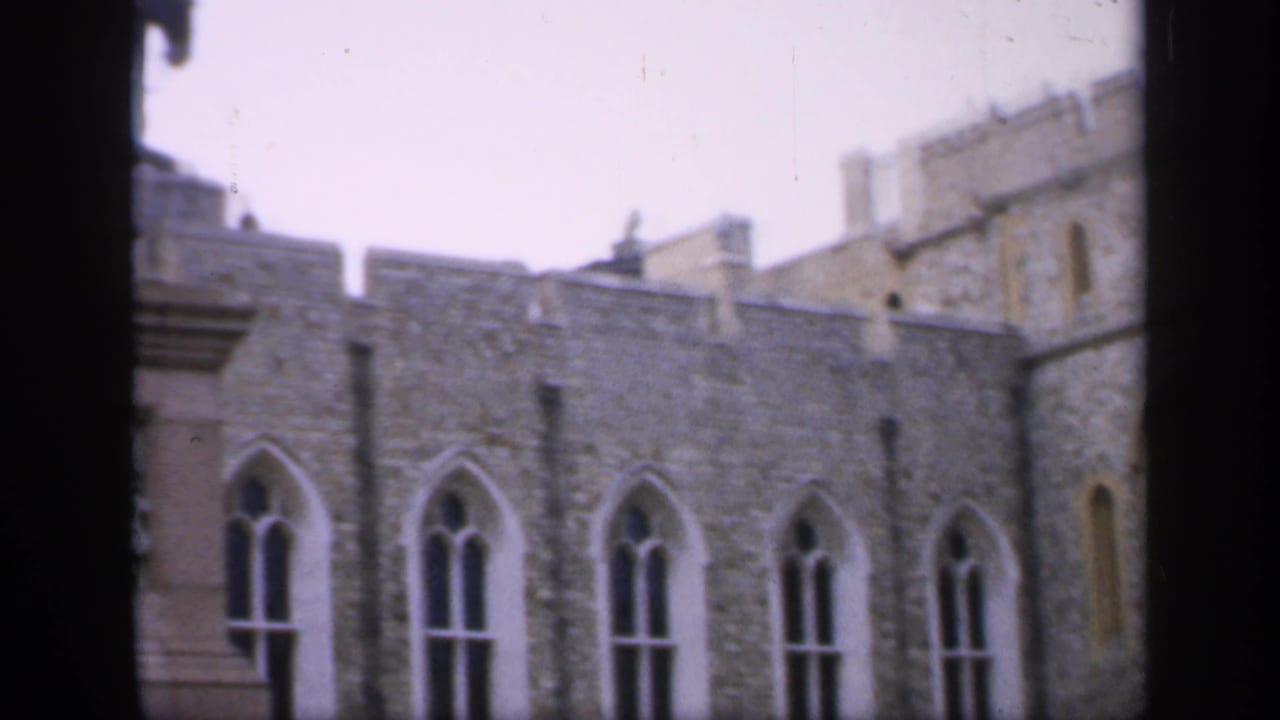 Stone castle wall with narrow Gothic windows and crenellated roofline.
