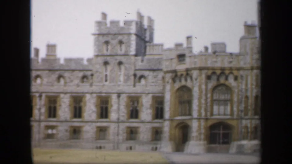 1949 England 8mm frame showing a broad stone castle elevation with crenellations, arched windows, and soft home-movie focus.