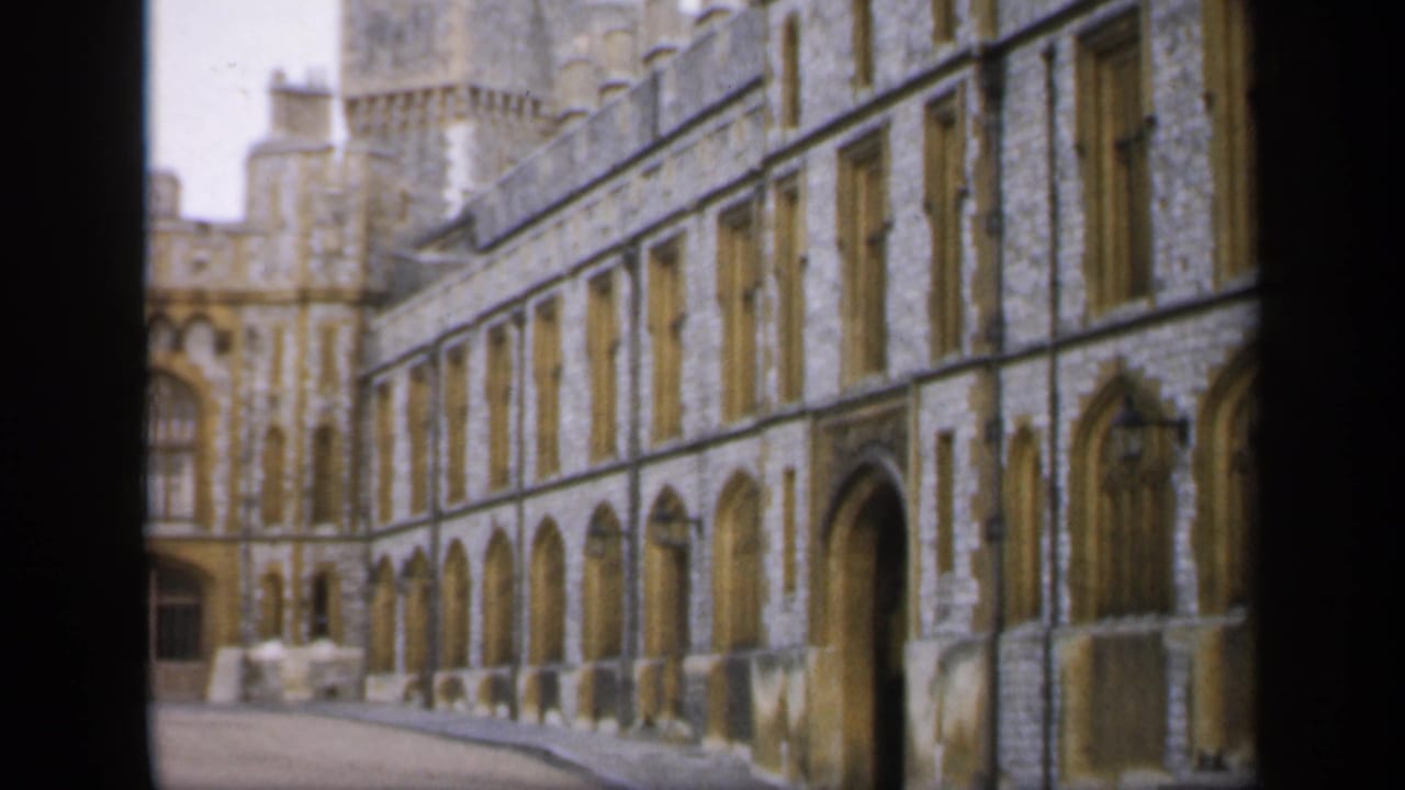 Stone castle courtyard with Gothic arches and tall windows.
