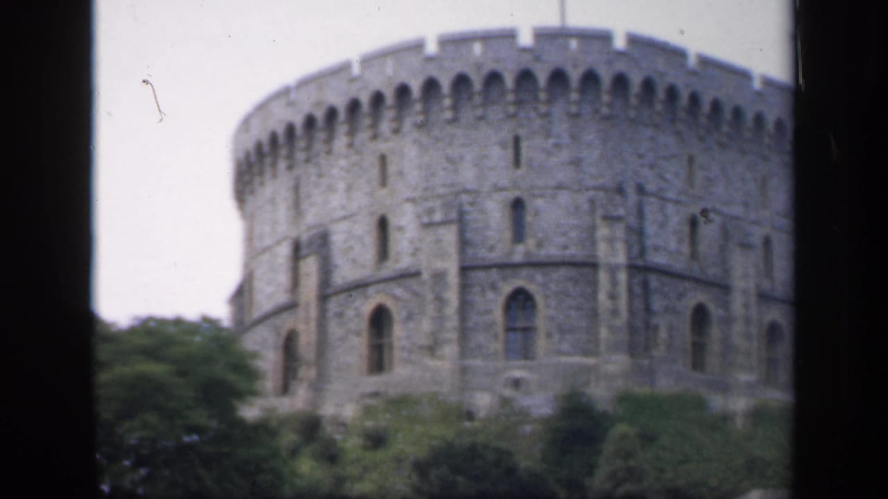 1949 England frame showing a large round stone castle tower with crenellations and trees in the foreground.