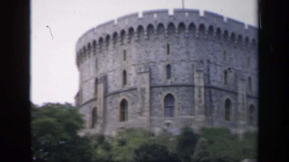 1949 England frame showing a large round stone castle tower with crenellations and trees in the foreground.