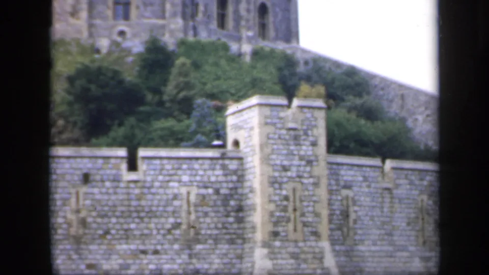 1949 England home-movie view of crenellated stone walls, a square pier, greenery, and part of the castle tower above.