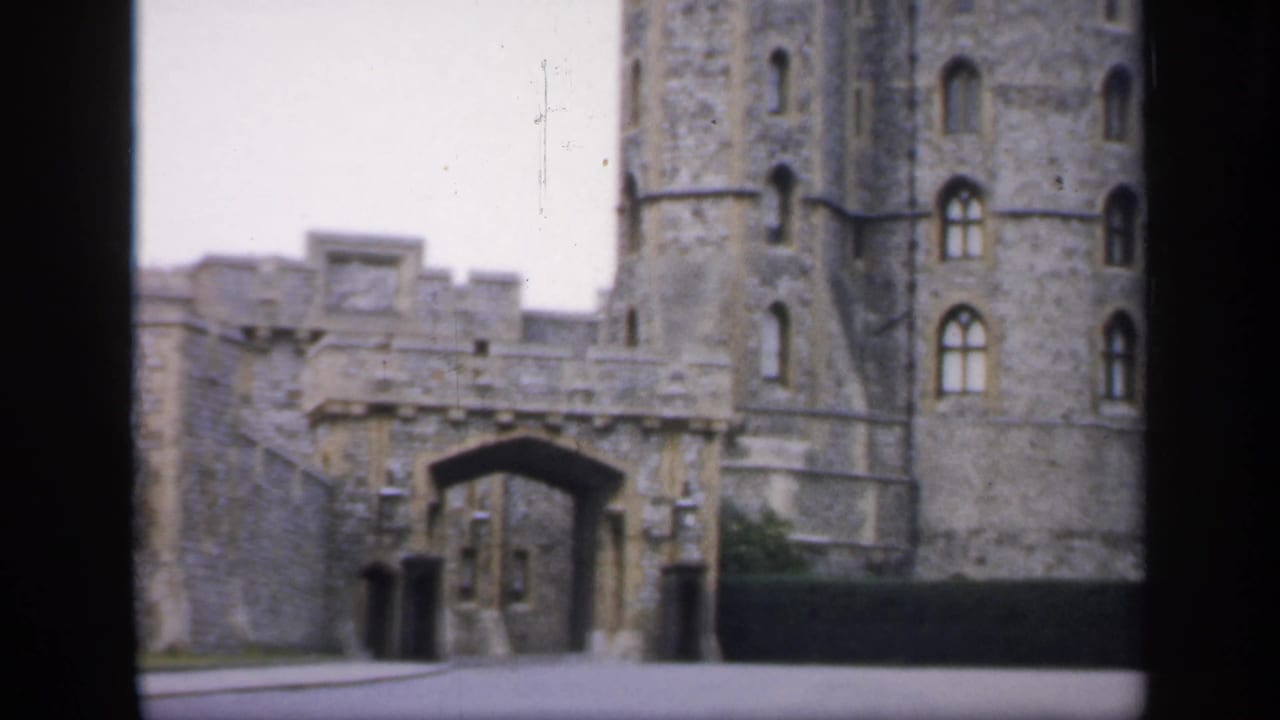 1949 England home-movie frame showing a stone castle exterior with an arched gateway and tall round tower.
