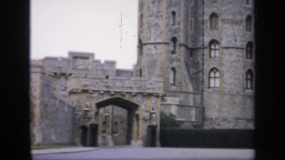 1949 England home-movie frame showing a stone castle exterior with an arched gateway and tall round tower.