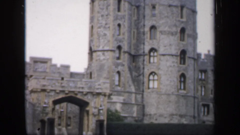 1949 England frame showing a castle gate and tall cylindrical stone tower, seen through soft 8mm home-movie exposure.