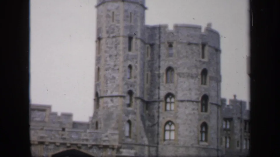 1949 England home-movie view of a tall round castle tower, arched windows, and adjoining stone walls.