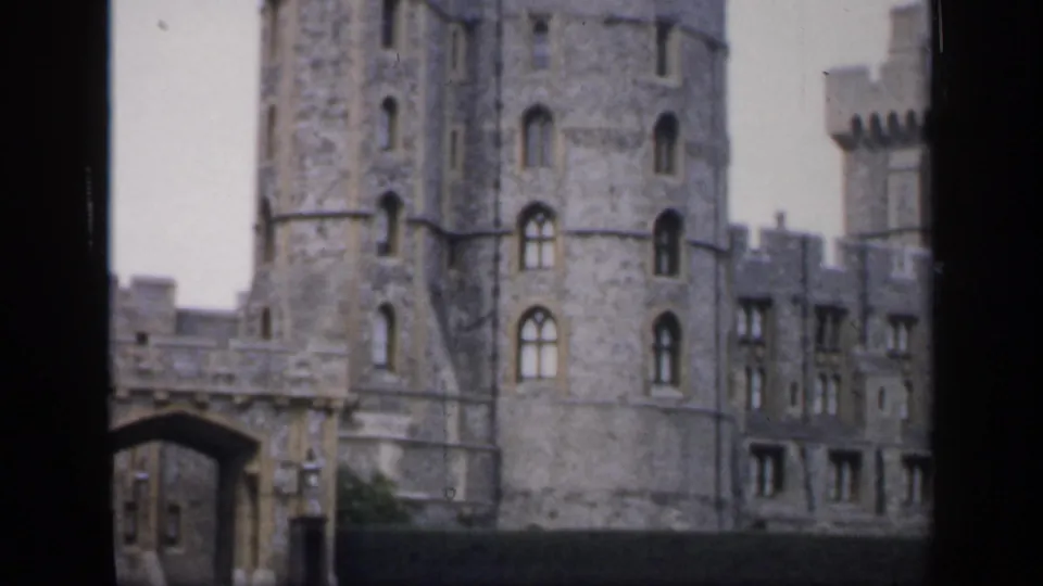 1949 England frame showing a stone castle tower, gateway, and adjoining building sections in a handheld 8mm view.