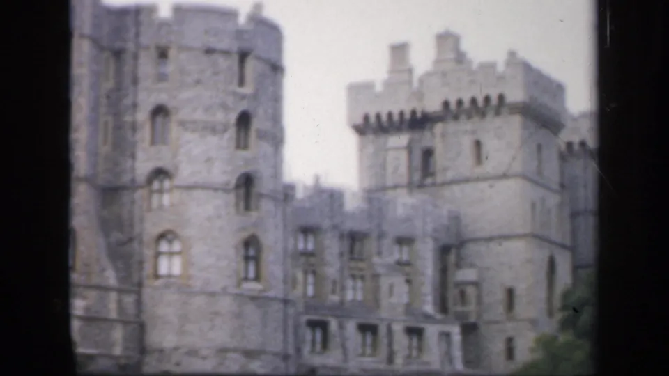 Soft 1949 England 8mm frame showing castle towers, crenellations, arched windows and a paved foreground during a visitor pan.