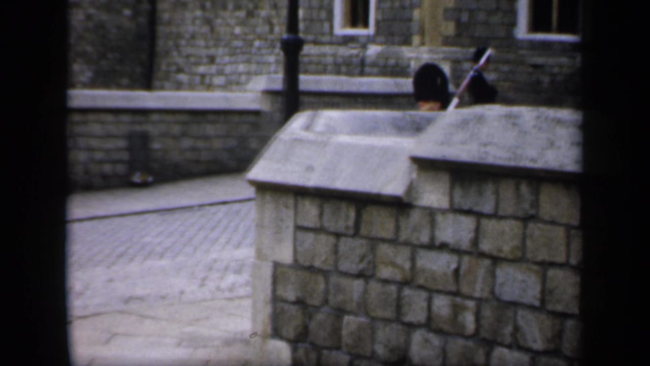 Guard partly hidden behind a stone wall in a paved courtyard.