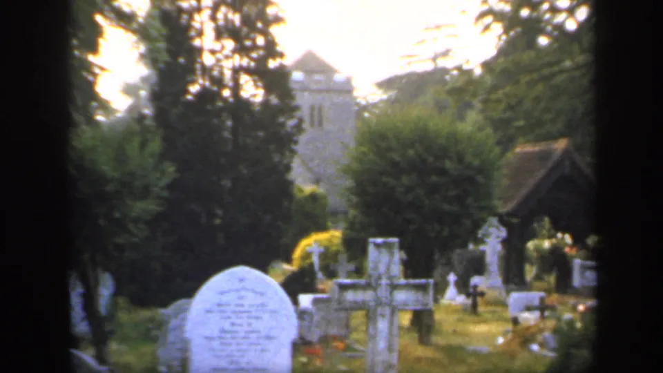 A brief churchyard view shows gravestones, trees, and a tower, likely near the same England travel-film setting.