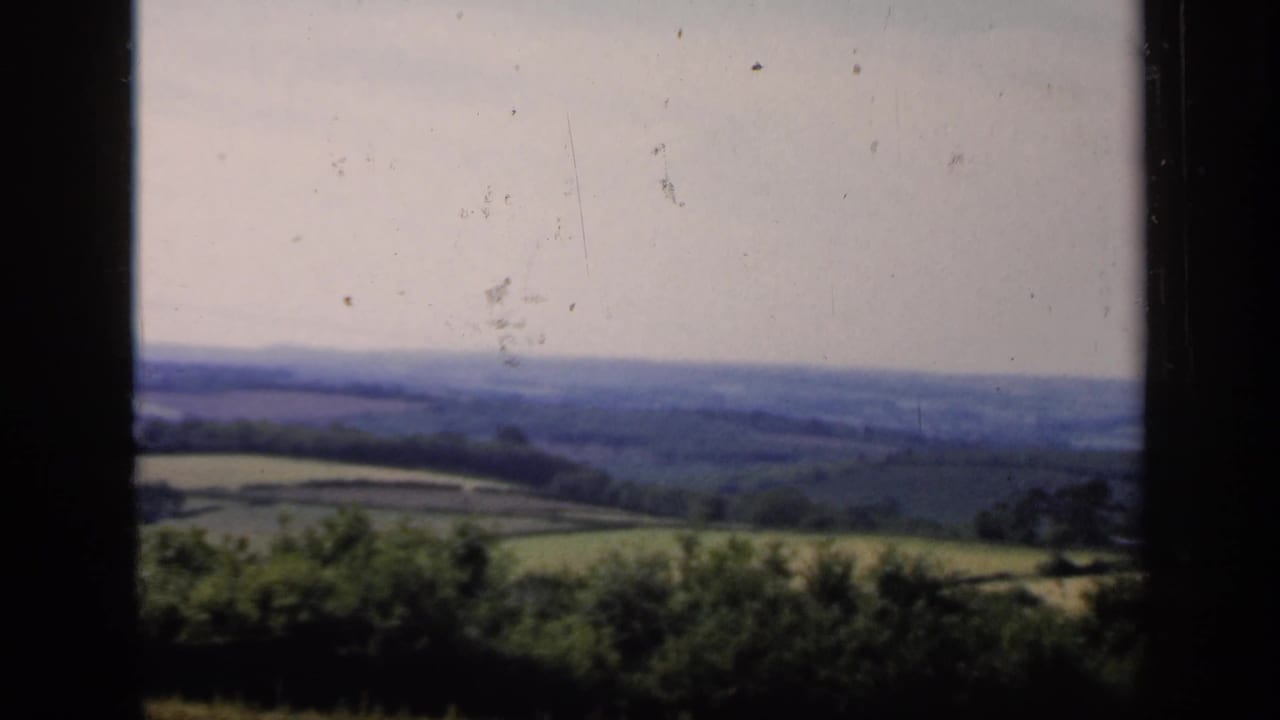 Distant farmland and hedgerows under a pale bright sky.