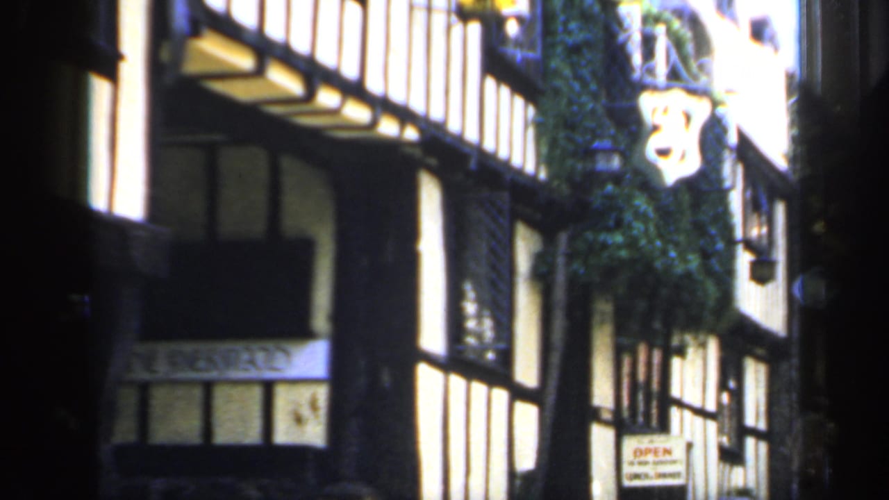 The final frame holds on the Tudor-style building in 1949 England, with bright plaster panels, dark beams, greenery, and visible signage.