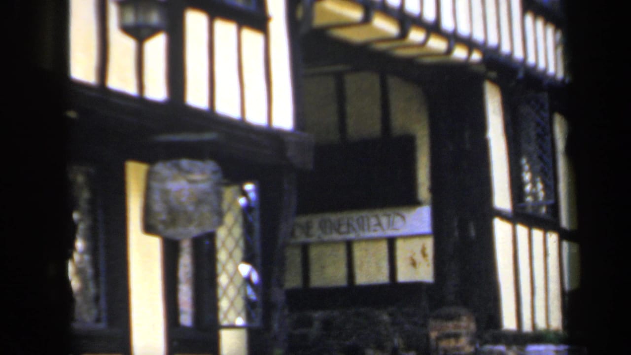 Close street facade with timber framing, signboard and lanterns.