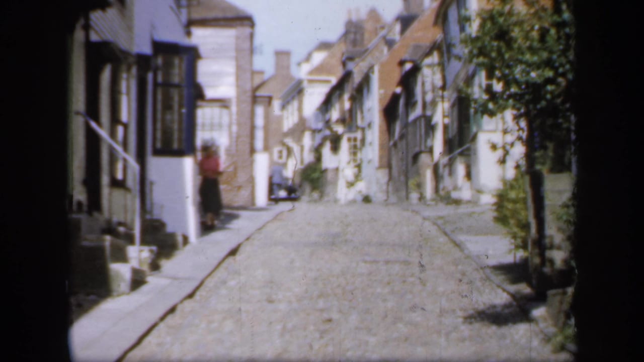 1949 England street view showing a narrow cobblestone lane, historic facades and a person standing near a building entrance.