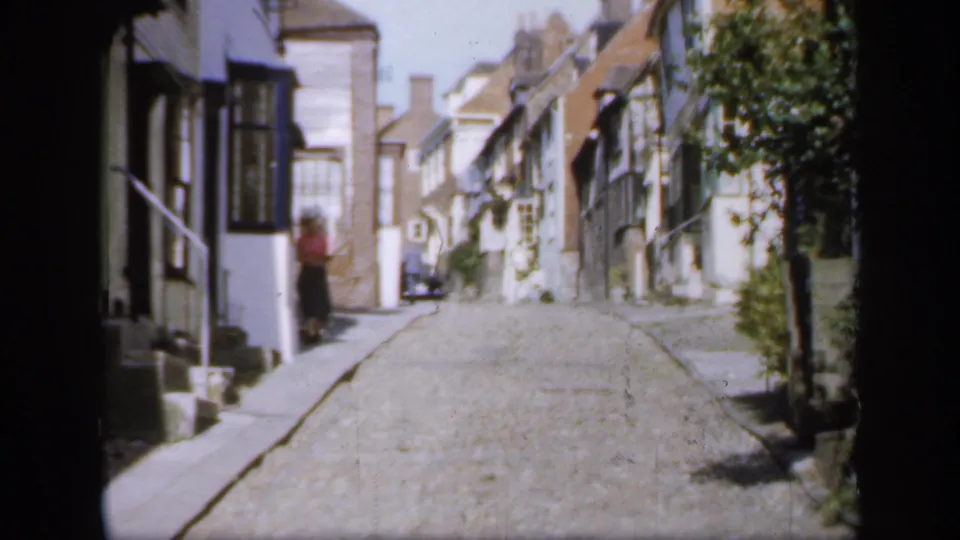 1949 England street view showing a narrow cobblestone lane, historic facades and a person standing near a building entrance.