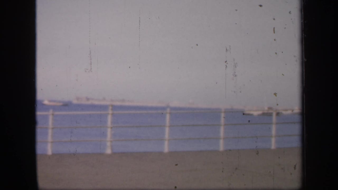 Waterfront railing with boats on the water, seen through a dark 8mm frame edge.