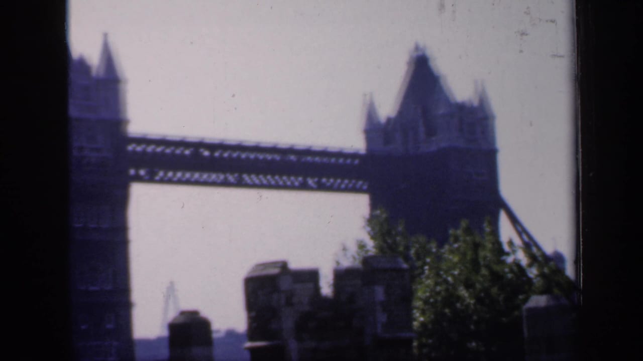 Tower Bridge seen through dark vertical window-frame edges with stonework in the foreground.