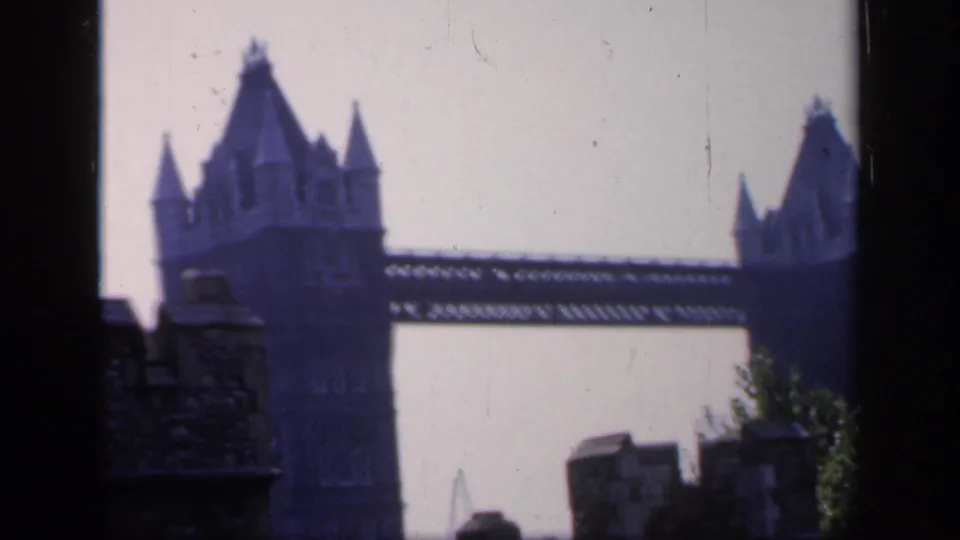 1949 London travel-film frame showing Tower Bridge's towers and upper span through a dark-framed viewpoint.