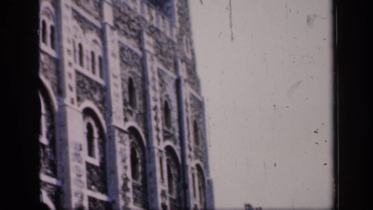 Close view of a large stone building with arched windows and a tower.