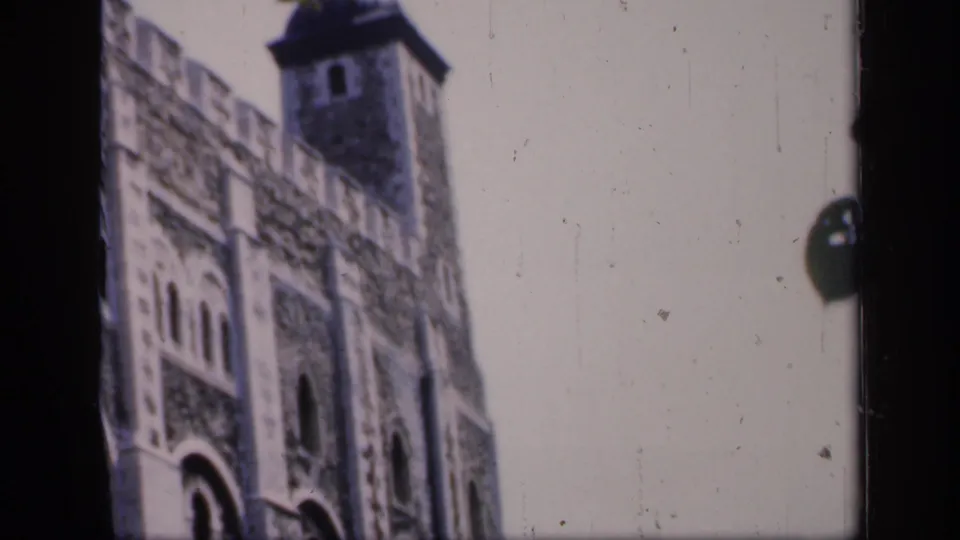1949 England frame with a soft, handheld view of a historic stone facade, arched window openings, and a tower roofline.