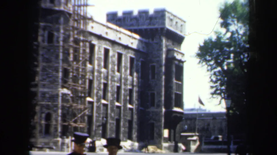 The frame emphasizes the historic stone fortress facade, with scaffolding and partial Yeomen Warder figures below.