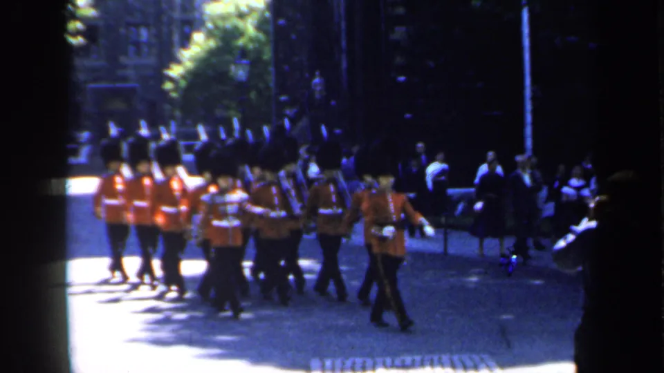 1949 England frame showing ceremonial guards moving out of formation view while spectators watch from the shaded street edge.