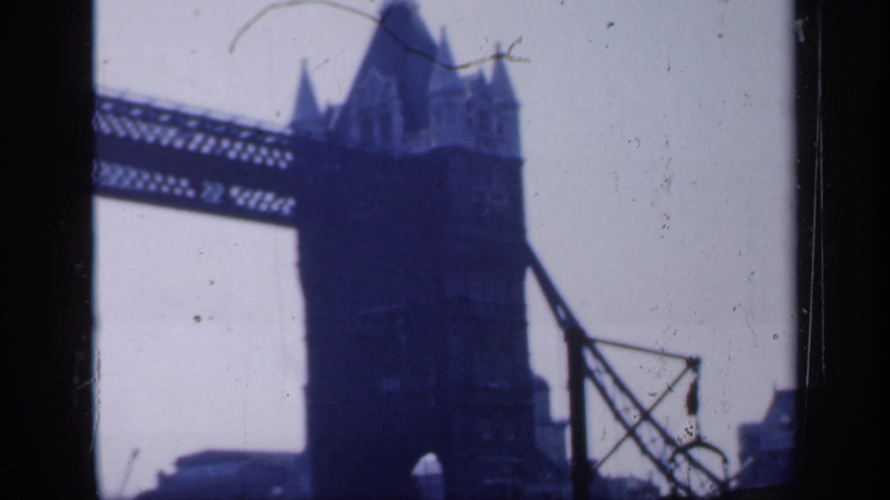 Soft blue-tinted view of Tower Bridge tower and upper walkway framed by dark film borders.