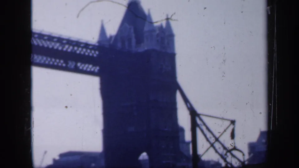 1949 England 8mm frame showing Tower Bridge in London, with a tower, upper walkway, pale sky, and heavy gate border.