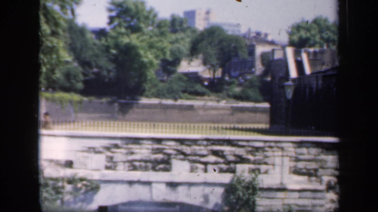 1949 England frame showing the park boundary, stone masonry, yellow fence, trees, and the edge of a fortified-looking structure.